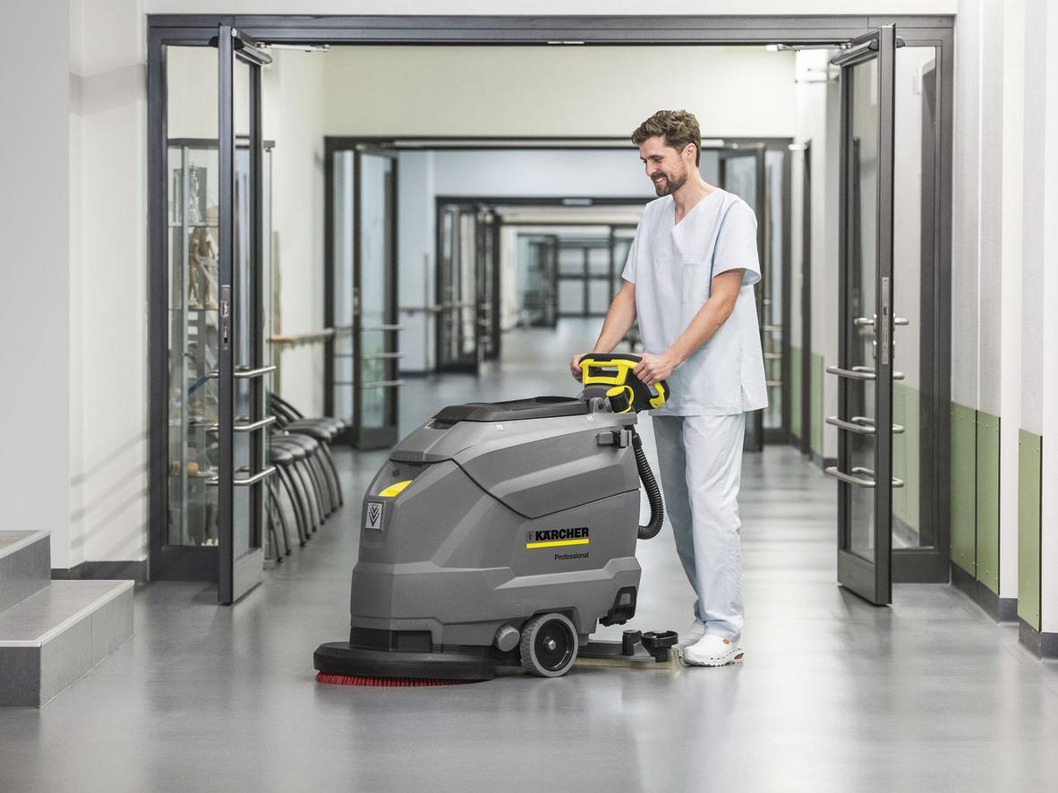 Hiệu suất làm sạch cao của Karcher BD 50/60 C Ep Classic (ảnh demo làm việc) - trước/sau sạch bóng hàng loạt sản phẩm trên kệ supermarket; imagePrompt: "Close-up of machine cleaning large supermarket floor, showing clean vs dirty area, motion blur on brush, bright lighting."