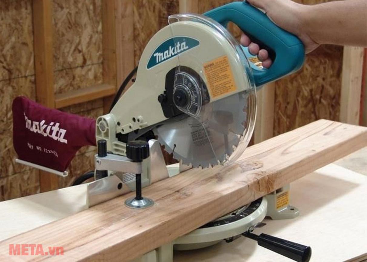 Makita LS1030N hoạt động mạnh mẽ trên công trường/xưởng; focus vào motor và lưỡi cắt hình ảnh demo (close-up) - ảnh minh họa lợi ích cắt nhanh và mịn, ít bavia (burr).”,