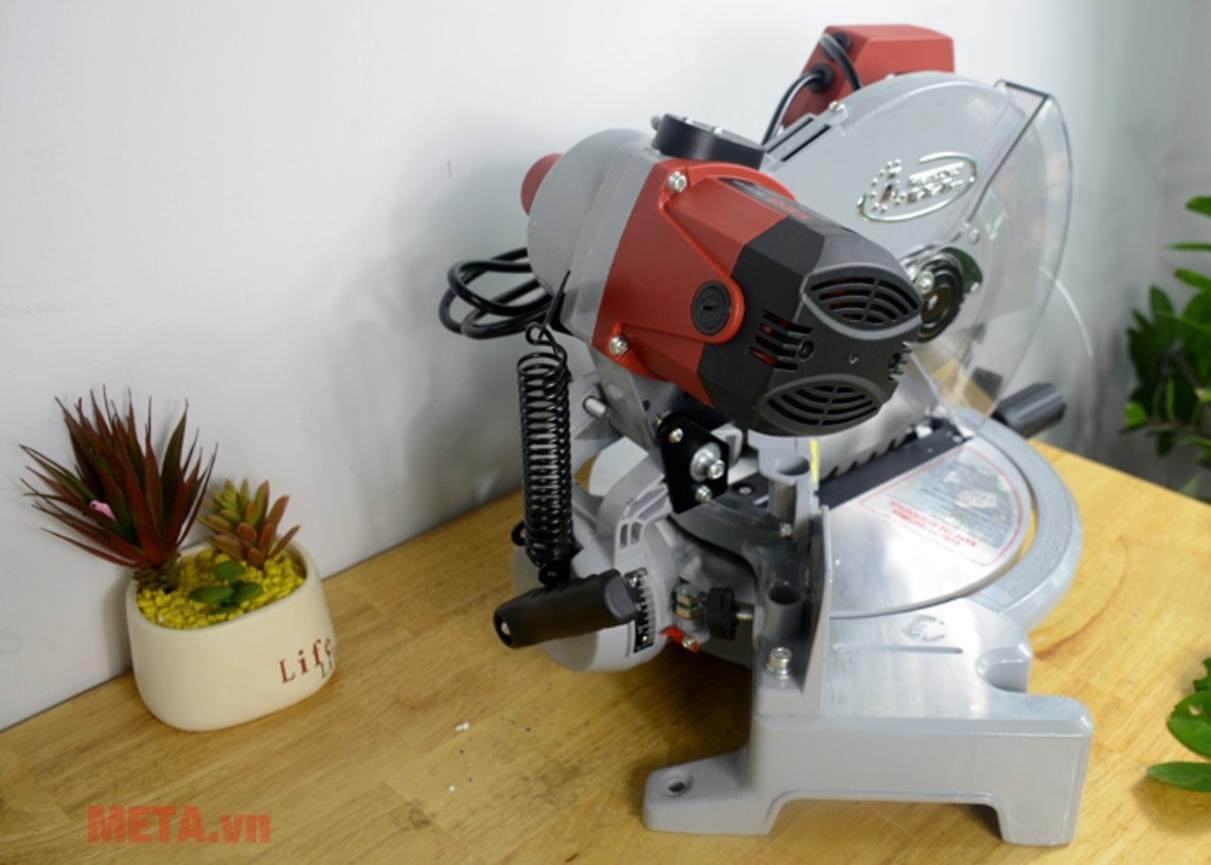 Mô tơ chổi than lõi dây đồng của FEG EG-1229 — bền và ổn định khi vận hành tại xưởng nhỏ nhanh bận rộn trông sáng sủa, có ánh sáng tự nhiên. Hiển thị chi tiết cuộn dây và vỏ bảo vệ máy (cận cảnh). Trong nền có miếng nhôm/ gỗ đã cắt sẵn và công nhân nhỏ đang vận hành máy để minh hoạ năng suất.